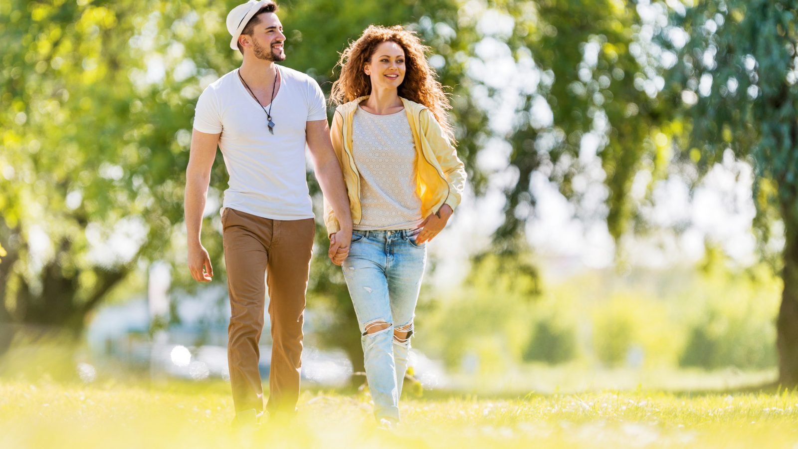 Couple souriant marchant dans un parc ensoleillé