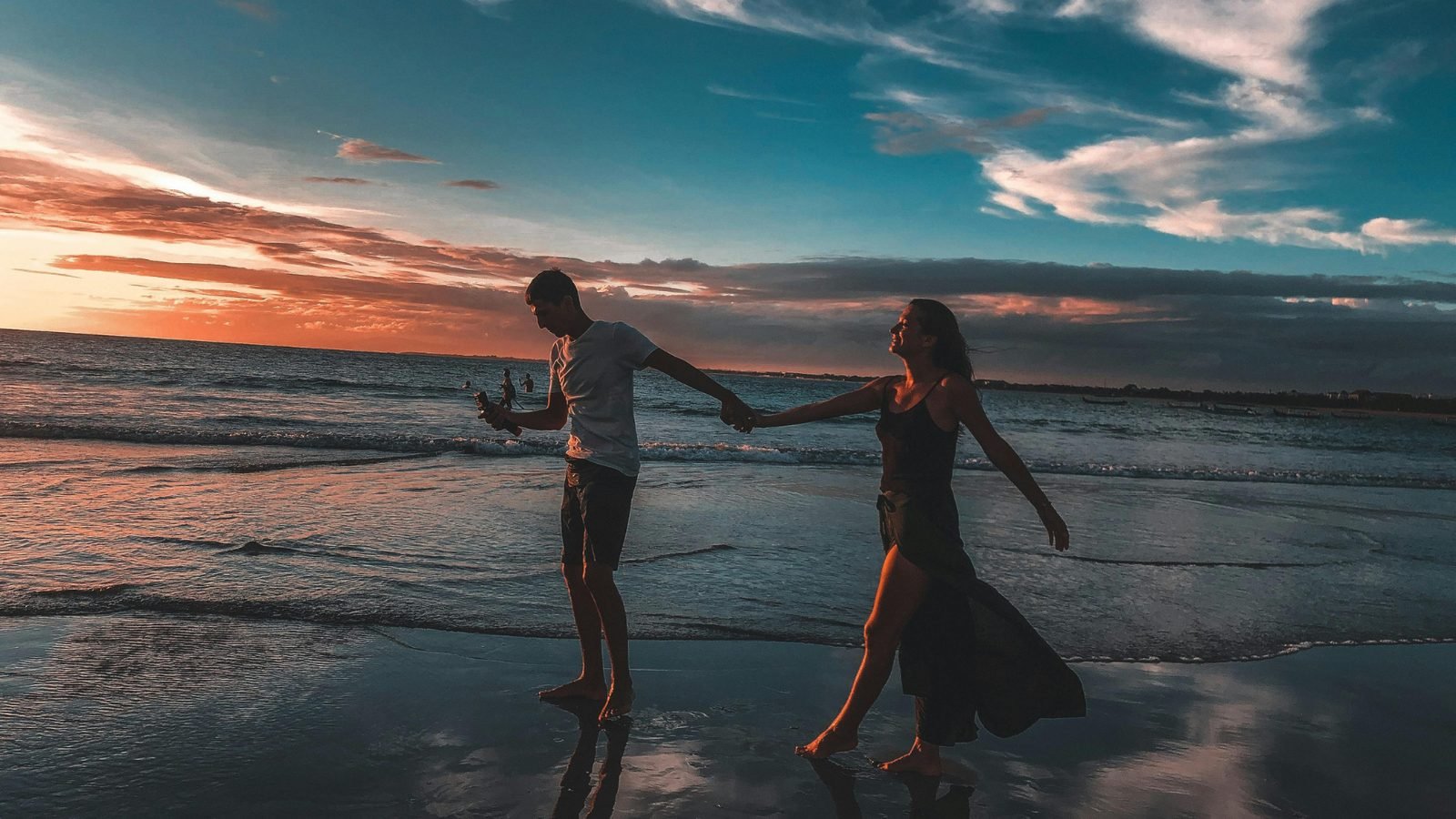 Couple se tenant la main au bord de l'eau au crépuscule